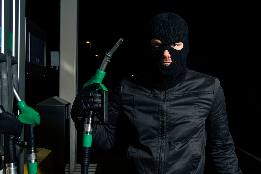 masked man using gas pump